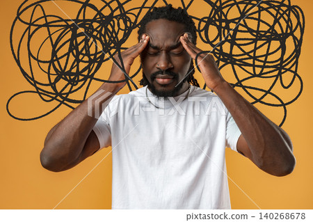Person holds head with hands in front of orange wall while looking stressed from thoughts Person holds head with hands in front of orange wall while looking stressed from thoughts 140268678