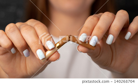 Person breaks a cigarette with hands during quit smoking effort in indoor setting Person breaks a cigarette with hands during quit smoking effort in indoor setting 140268704