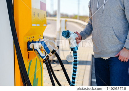 Charging an electric car at a public station during daylight in a busy area 140268716