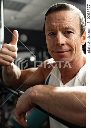 Man gives thumbs up while working out in gym during daylight hours 140268777