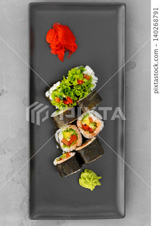Fresh sushi rolls served on a black plate with garnishes and condiments Fresh sushi rolls served on a black plate with garnishes and condiments 140268791