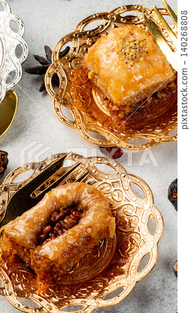 Baked sweets on golden plates with nuts and syrup arranged on a gray surface Baked sweets on golden plates with nuts and syrup arranged on a gray surface 140268808