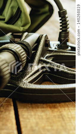 Metal detector device rests on wooden table with backpack nearby in a park Metal detector device rests on wooden table with backpack nearby in a park 140268819