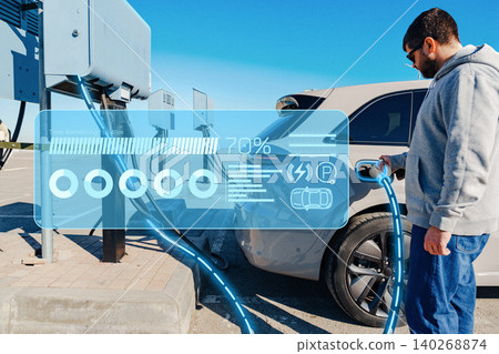 Electric car charging station being used by a person in a sunny outdoor setting Electric car charging station being used by a person in a sunny outdoor setting 140268874