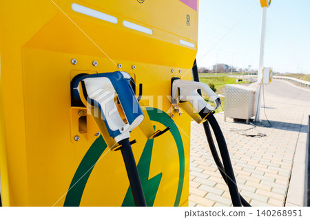 Electric car charger in a public charging station during daylight hours Electric car charger in a public charging station during daylight hours 140268951