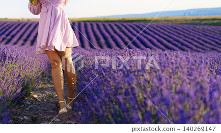 Woman walks through a lavender field in the daytime with rows of flowers Woman walks through a lavender field in the daytime with rows of flowers 140269147
