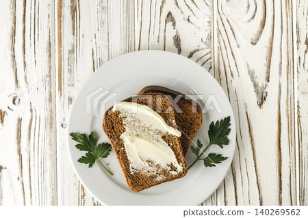 Buttered slice of rye bread on wooden table Buttered slice of rye bread on wooden table 140269562
