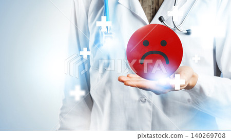 Doctor holds red unhappy face symbol while caring for patients in medical setting 140269708