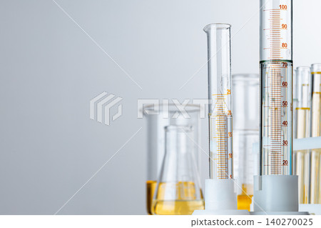 Laboratory glassware with yellow oily liquid on grey background Laboratory glassware with yellow oily liquid on grey background 140270025