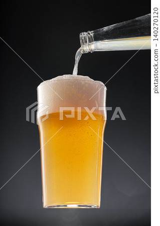Beer pouring into glass on black background Beer pouring into glass on black background 140270120