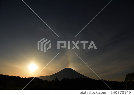 富士山旁冉冉升起的太陽反射在薄薄的雲層上，形成一道弧形彩虹，彷彿從富士山頂升起。 140270149