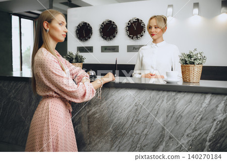 Blonde woman hotel guest checking-in at front desk in hotel Blonde woman hotel guest checking-in at front desk in hotel 140270184