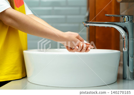 Close up of a woman washing her hands in a bathroom sink Close up of a woman washing her hands in a bathroom sink 140270185