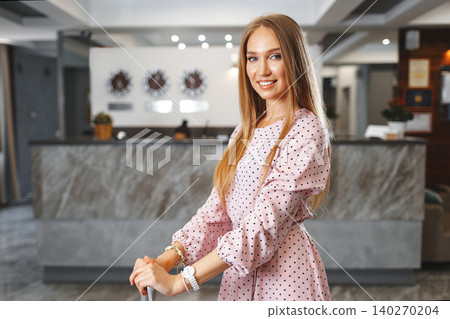 Young attractive woman with packed suitcase standing in hotel lobby Young attractive woman with packed suitcase standing in hotel lobby 140270204