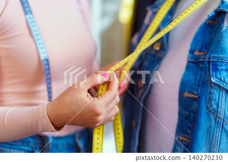 Young woman seamstress making measurements with mannequin 140270230