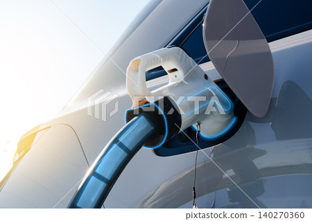 Electric car charges at a station during evening hours on a sunny day Electric car charges at a station during evening hours on a sunny day 140270360