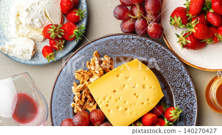 Cheese and fruit platter with wine glass on a tabletop during a gathering Cheese and fruit platter with wine glass on a tabletop during a gathering 140270427