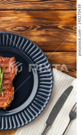 Freshly cooked meat on a dark plate ready for dinner on a wooden table Freshly cooked meat on a dark plate ready for dinner on a wooden table 140270439