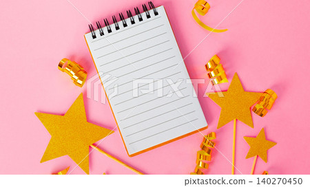 Blank notebook with gold stars and curly ribbons on a pink background for planning purposes 140270450
