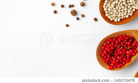 Different types of pepper in wooden spoons on a white background Different types of pepper in wooden spoons on a white background 140270470