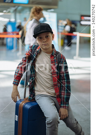 boy sitting on suitcase in airport waiting for flight. Travel concept. Vertical photo boy sitting on suitcase in airport waiting for flight. Travel concept. Vertical photo 140270742