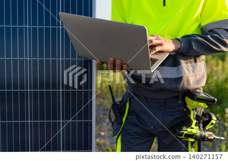 Engineer with laptop next to solar panel Engineer with laptop next to solar panel 140271157