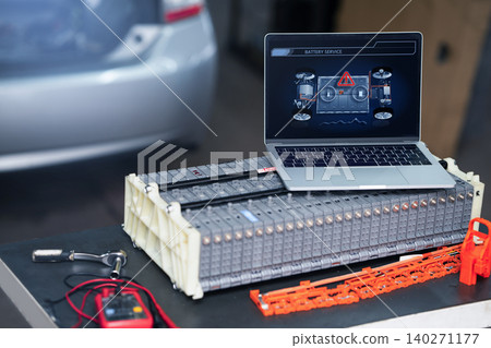Serviceman repairs electric battery pack of hybrid car using laptop Serviceman repairs electric battery pack of hybrid car using laptop 140271177