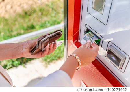 Woman paying cash at automated parking payment machine, inserting euro banknote while holding parking ticket and wallet at self service terminal Woman paying cash at automated parking payment machine, inserting euro banknote while holding parking ticket and wallet at self service terminal 140271612