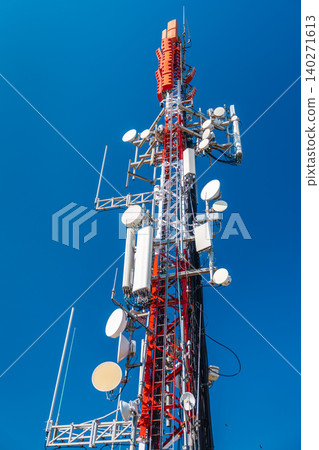 Cellular communication tower with multiple antennas and transmitters against clear blue sky 140271613