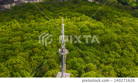 Aerial close up of telecommunications tower above dense green forest in Germany with wireless antenna infrastructure surrounded by spring woodland Aerial close up of telecommunications tower above dense green forest in Germany with wireless antenna infrastructure surrounded by spring woodland 140271626