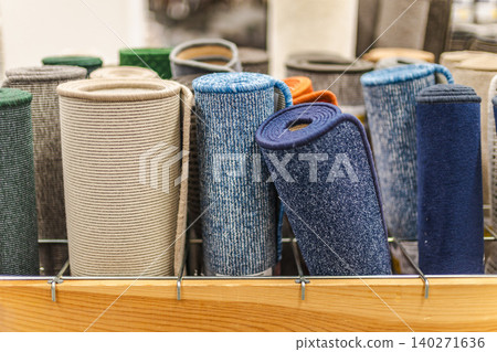 Rolled carpet samples and colorful floor mats displayed in home improvement store 140271636