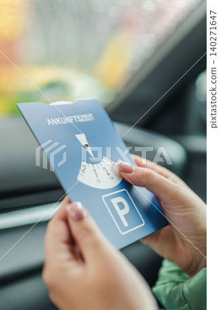 Driver holding European parking disc inside parked car before leaving vehicle Driver holding European parking disc inside parked car before leaving vehicle 140271647