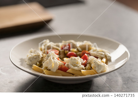 Penne pasta with mozzarella, pesto and fresh cherry tomatoes Penne pasta with mozzarella, pesto and fresh cherry tomatoes 140271735