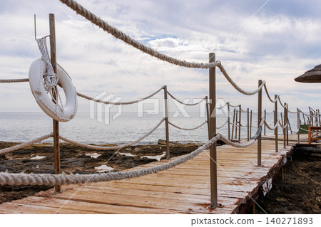 Rope fence walkway with a white lifebuoy by Mediterranean Sea in Paphos, Cyprus. Rope fence walkway with a white lifebuoy by Mediterranean Sea in Paphos, Cyprus. 140271893