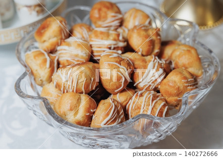 Golden choux pastries sit in a clear glass bowl Golden choux pastries sit in a clear glass bowl 140272666