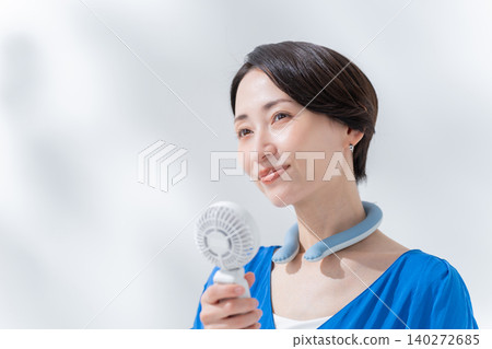 A woman using an ice ring and a handheld fan in the summer. A woman using an ice ring and a handheld fan in the summer. 140272685