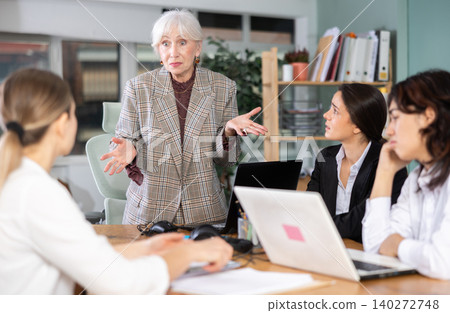 Standing senior woman scold to round table gathering female staff at office 140272748