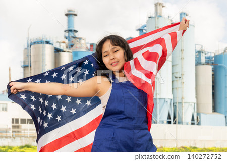 Happy young woman with flag of the USA against background of factory Happy young woman with flag of the USA against background of factory 140272752