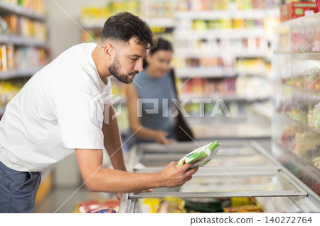 Man customer in supermarket search, choose product in fridge. Man customer in supermarket search, choose product in fridge. 140272764