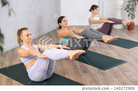 Young woman practicing boat pose in yoga studio Young woman practicing boat pose in yoga studio 140272908