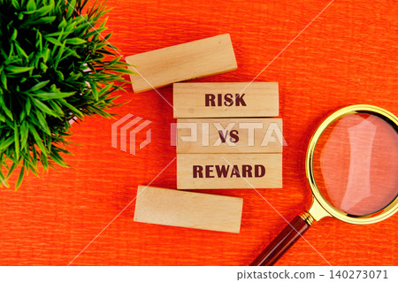 Wooden blocks spell out risk vs reward beside a magnifying glass and a small plant on a bright orange surface, inviting reflection on choices and outcomes Wooden blocks spell out risk vs reward beside a magnifying glass and a small plant on a bright orange surface, inviting reflection on choices and outcomes 140273071