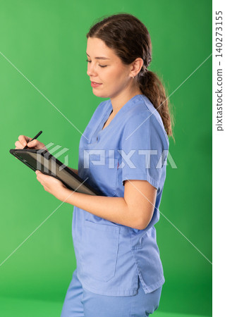 Young female medic in blue uniform checking data on tablet Young female medic in blue uniform checking data on tablet 140273155