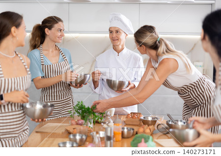 Mature female cook holding bowl and whisk Mature female cook holding bowl and whisk 140273171