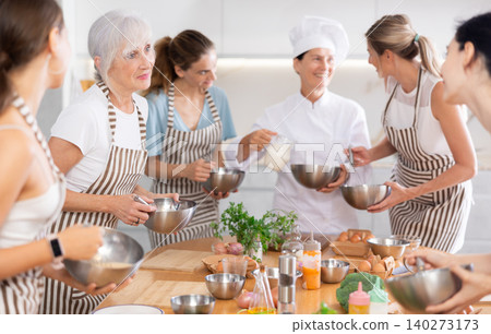 Elderly woman teaching cooking to group of woman Elderly woman teaching cooking to group of woman 140273173