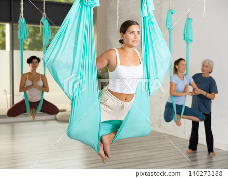 Fit young woman doing fly yoga stretching exercises in fitness training gym loft classroom. Sport healthy lifestyle concept 140273188