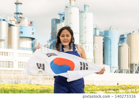 Happy asian girl in work clothes with flag of south korea standing in front of industrial scenery Happy asian girl in work clothes with flag of south korea standing in front of industrial scenery 140273316