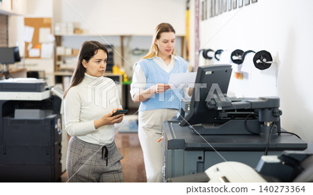 Team of professionals works on printing equipment in printer shop 140273364