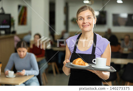 Young female waiter carries order for cafe customer Young female waiter carries order for cafe customer 140273375