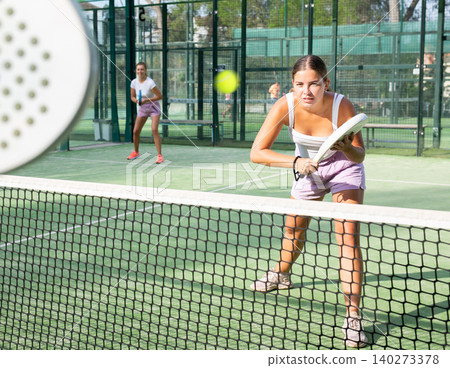 Young woman in shorts playing padel tennis on court 140273378