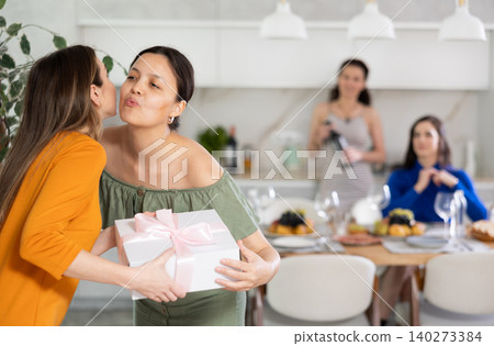 Girls hug and kiss on cheek when they meet, guest gives gift to birthday woman Girls hug and kiss on cheek when they meet, guest gives gift to birthday woman 140273384